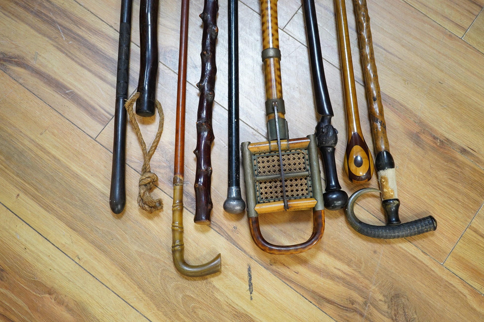 An Edwardian oak stickstand and sundry walking sticks including a bamboo shooting stick, silver topped cane etc. condition varies